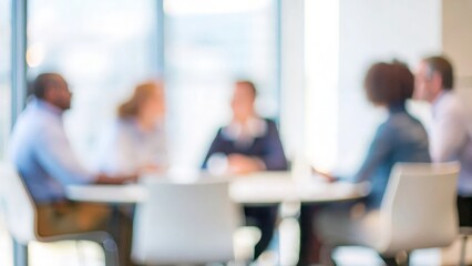 A blurred image of a small group of professionals discussing project details in a meeting room.
