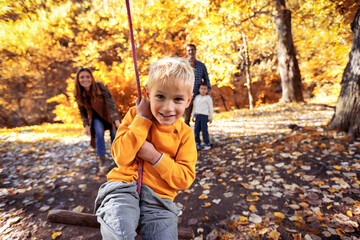 Happy family having fun on a swing ride in the autumn park