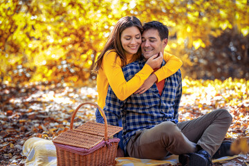 Happy young couple having picnic in autumn park.