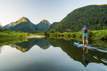 Man paddling SUP on relaxing calm water with mountain view