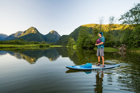 Man wearing lifejacket standing on paddle bpard