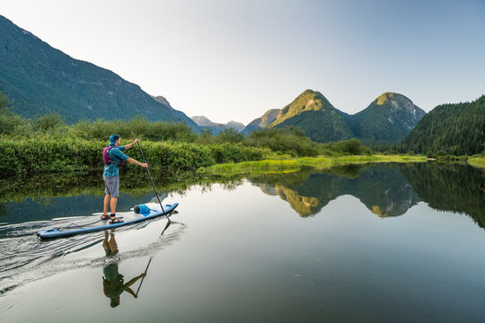 Side view of man paddling a SUP in scenic location, B.C. Canada