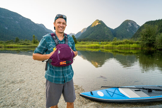 Portrait of healthy outdoorsman standing next to SUP