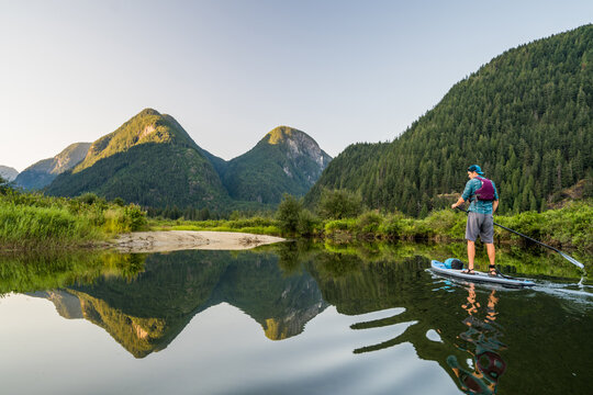 Man paddling SUP on relaxing calm water with mountain view