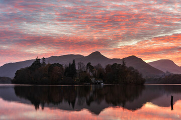 Amazing atmospheric sunset landscape of Derwentwater in Lkae District during Autumn with dramatic pink sky and reflections in lake