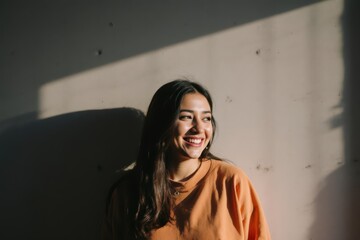Fototapeta premium Smiling woman under shadow in front of concrete wall
