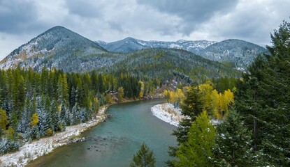 Autumnal mountain river scene with fresh snow. A winding river flows through a valley with colorful...