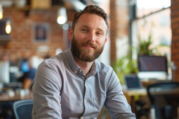 Obraz premium Young professional with a beard is smiling in a busy office environment