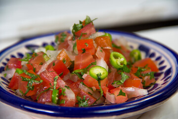 Pico de gallo mexican spicy sauce over a traditional Talavera clay bowl.