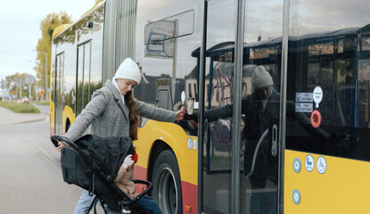 Mother with baby carriage getting into a bus on the station. Woman with stroller in the city. Low-floor bus. Close-up. The concept of solo parenting and city transport. © Forewer