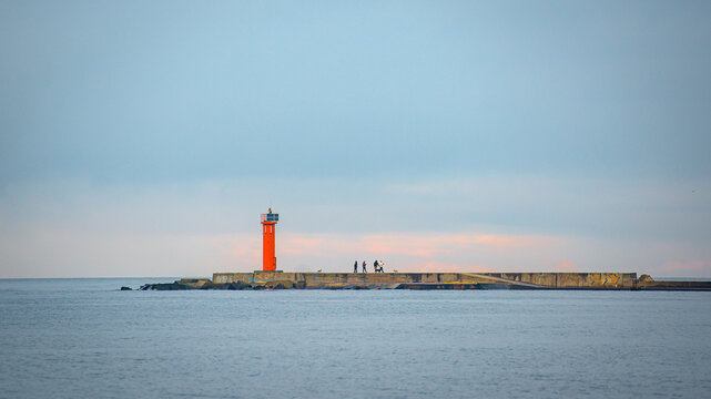lighthouse at the end of breakwaters in the port - Powered by Adobe