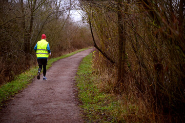 Obraz premium A man wearing safety waistcoat running in a park