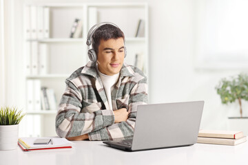Young man with headphones sitting and looking at a laptop