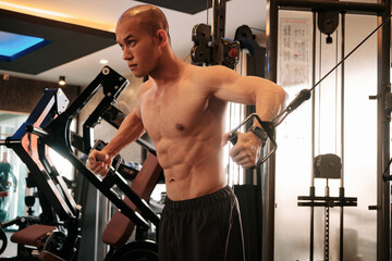 A man is performing a cable crossover exercise at the gym. The image showcases his defined chest and upper body muscles, emphasizing his intense workout routine and commitment to fitness.