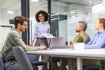 Happy four business people executive team working at laptop having discussion at office meeting showing financial project