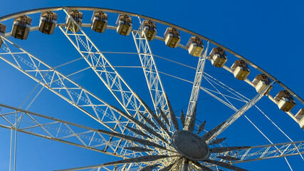 A large Ferris wheel set against a clear blue sky, symbolizing leisure and amusement during summer...