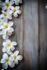 Obraz premium Delicate white frangipani flowers with yellow centers arranged on rustic wooden boards.