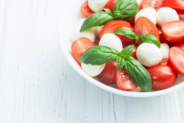 Basil leaves , cherry tomatoes and mozzarella cheese . In bowl food photography