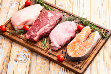 Mix of raw meat and fish . Salmon , beef , pork , chicken staek . Top view