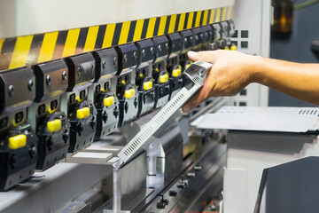 Close up the bending machine operator hold the sheet metal parts.