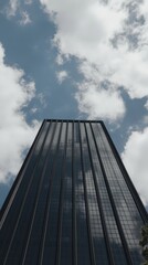 Fototapeta premium A tall, reflective skyscraper stretches into a partly cloudy sky, showcasing modern architectural elegance and urban business environments.