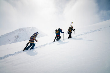 Group of travelers snowboarders and skiers, tourists with backpacks in winter snowy mountains. Ski...