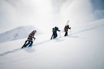 Selbstklebende Fototapeten Group of travelers snowboarders and skiers, tourists with backpacks in winter snowy mountains. Ski tourism concept © yanik88