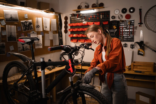 Female bicycle mechanic repairing bicycles in a workshop or her garage. Concept of hobby and small business