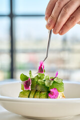 A gourmet dish featuring a delicate piece of fish, surrounded by a vibrant arrangement of fresh vegetables and edible flowers.