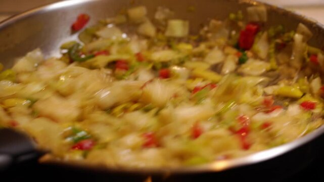 plan fixe, sur un remuage d'une po&ecirc;l&eacute;e de l&eacute;gumes vari&eacute;s, &agrave; l'aide d'une belle po&ecirc;le inox de grande taille