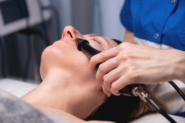 Woman undergoing skin tightening by activating a natural process. A cosmetologist performs a skin rejuvenation procedure in a spa. Aesthetic medical cosmetology