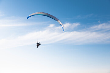 Paragliding sport, man alone flies in blue sky with clouds, freedom and loneliness. Hobby for adults