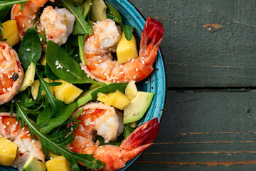 Salad with tiger shrimps , avocado and mango . Top view