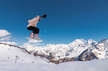 Athletic Caucasian woman in cap jumping from ski jump high in mountains doing flying trick against...
