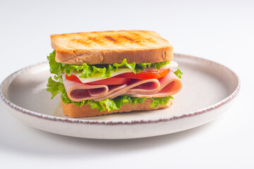 Close-up of two sandwiches with bacon, salami, prosciutto and fresh vegetables on rustic wooden cutting board. Club sandwich concept