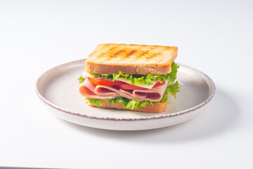 Close-up of two sandwiches with bacon, salami, prosciutto and fresh vegetables on rustic wooden cutting board. Club sandwich concept