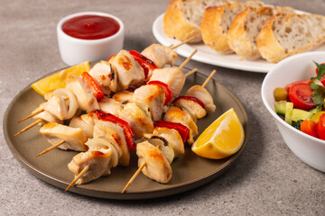 Delicious grilled chicken skewers with capsicum, lemon, salad and ketchup on a plate over the table. Chicken kebab. Healthy food concept.