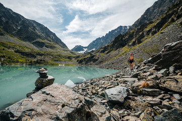 a tourist girl with a backpack walks through the Altai mountains in summer