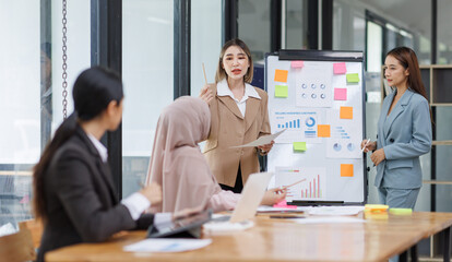 Group of asian professionals collaborating and working together in a  office. They are discussing project solutions and working on paperwork. The team looks happy, successful.
