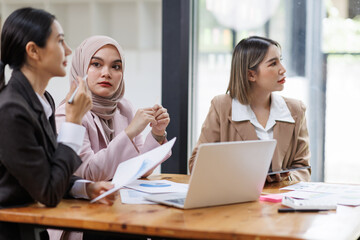 Group of asian professionals collaborating and working together in a  office. They are discussing project solutions and working on paperwork. The team looks happy, successful.

