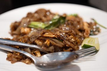 Stir fried rice noodle with black soy sauce and pork and kale. Thai food