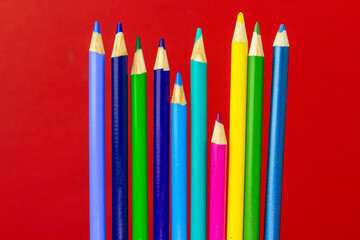 Vibrant Array of Colored Pencils Against a Bold Red Background.
