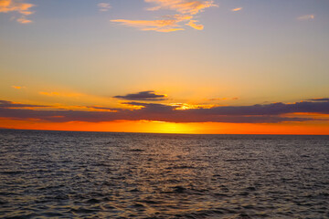 Landscape A breathtaking sunset paints the sky with hues of orange and yellow, casting a warm glow on the calm ocean and the rocky shoreline. (3)
