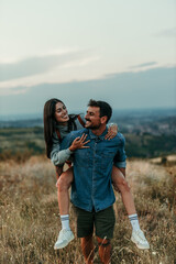 A couple sharing laugh and funny moment in a meadow as the sun dips low. Copy space