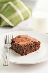 Chocolate brownie with milk and green napkin.