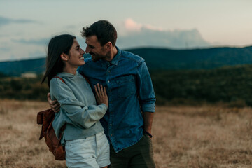 Romantic couple walking hand in hand through a golden meadow at sunset.