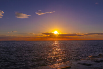 Landscape A stunning sunset paints the sky with vibrant hues of orange and purple as the sun dips below the horizon, reflecting its warmth on the calm ocean.