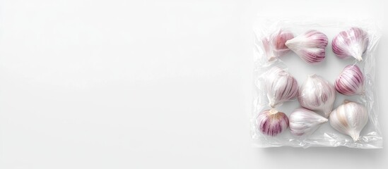 Aerial view of fresh garlic cloves in plastic packaging on white background with space for text and design elements