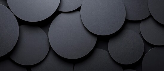 Black Circular Cardboard Shapes of Varying Sizes Against Dark Background with Empty Copyspace for Text or Graphics Display