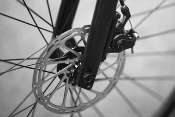Fototapeta premium Close-up of a bicycle wheel showcasing metallic spokes and hub against a blurred green background, emphasizing craftsmanship and outdoor activity. Ideal for cycling, transportation, and fitness themes